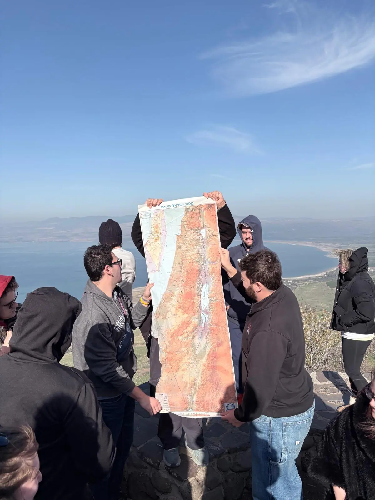 Travelers holding a map of Israel above the Sea of Galilee
